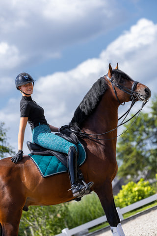 Woman wearing our Riding Breeches in a blue color and a saddle pad in the same color.
